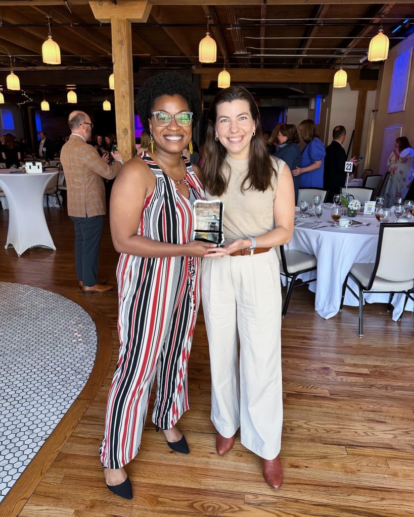 two women holding award for most impactful project for education equity in birmingham